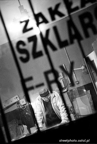 U szklarza. Sylwetka w oknie, ludzie w fotografii