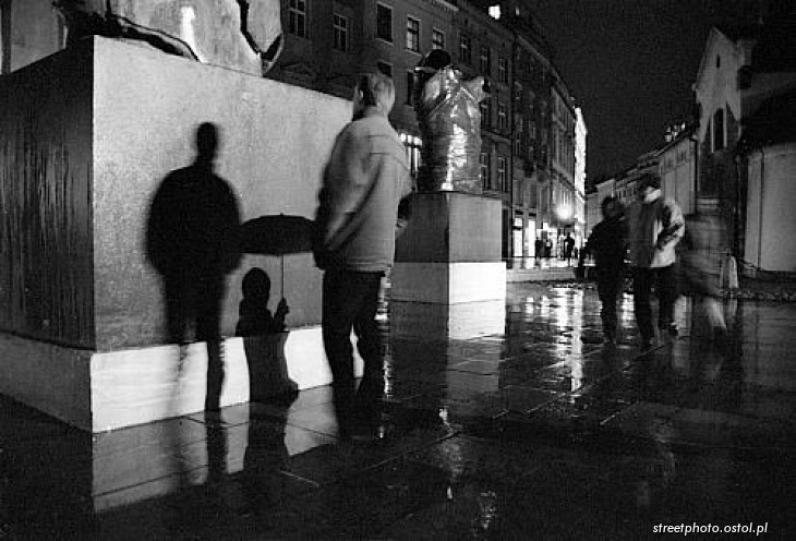 Postać z parasolką, Kraków, Rynek Główny, deszcz, cień.
